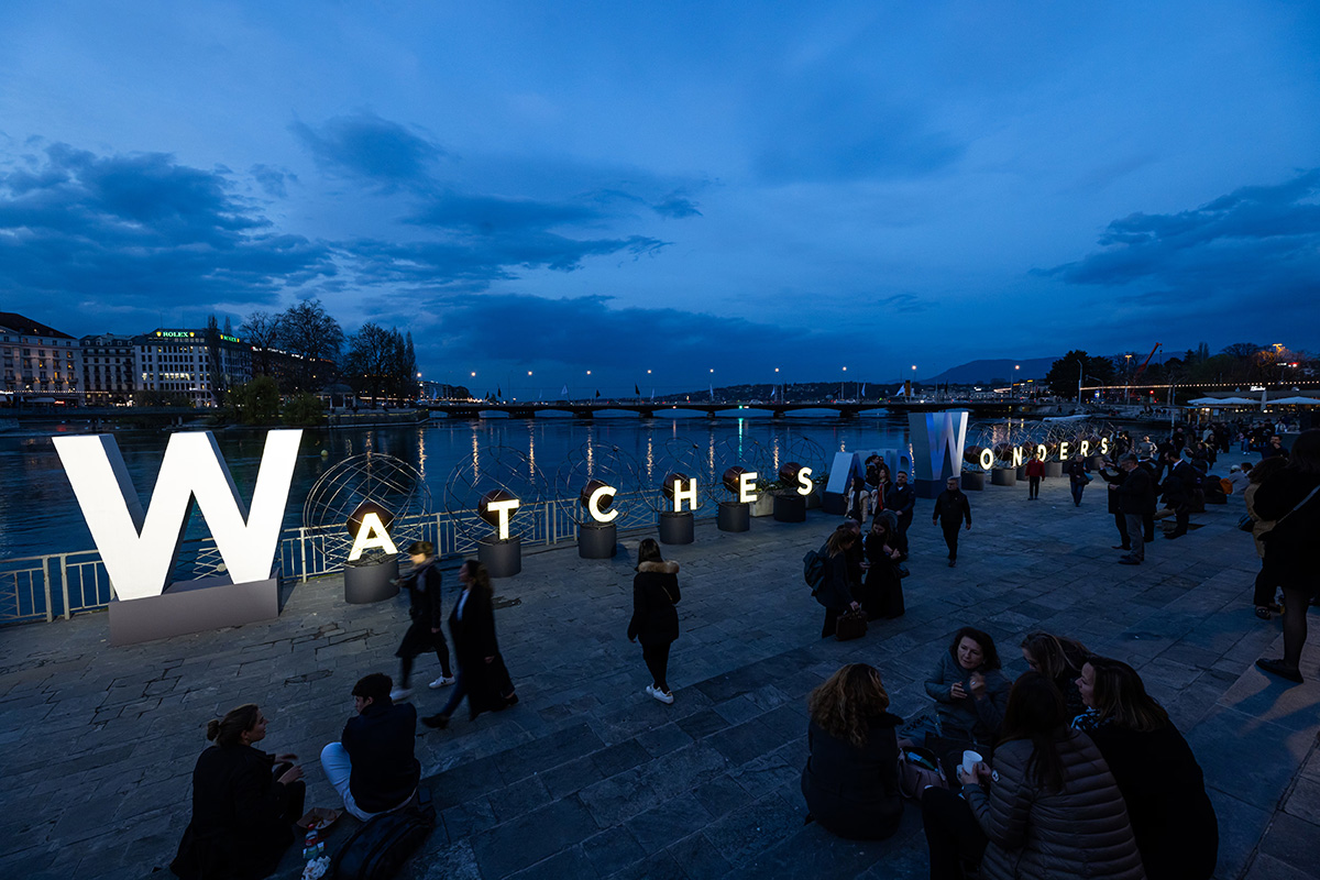 Messbesucher auf einer Promenade vor den Leuchtbuchstaben «Watches and Wonders» in Genf.