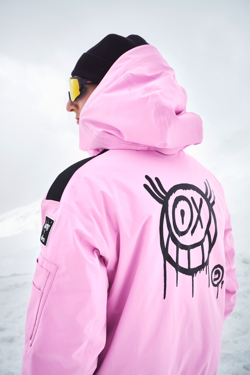 Rückenansicht einer Person in pinker Elho-Bomberjacke mit großem schwarzem Graffiti-Smiley von André Saraiva, Schneelandschaft im Hintergrund