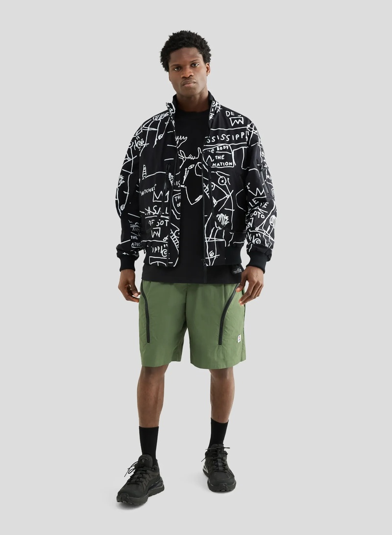 Model trägt schwarze Bomberjacke von Elho mit weißen Basquiat-Prints