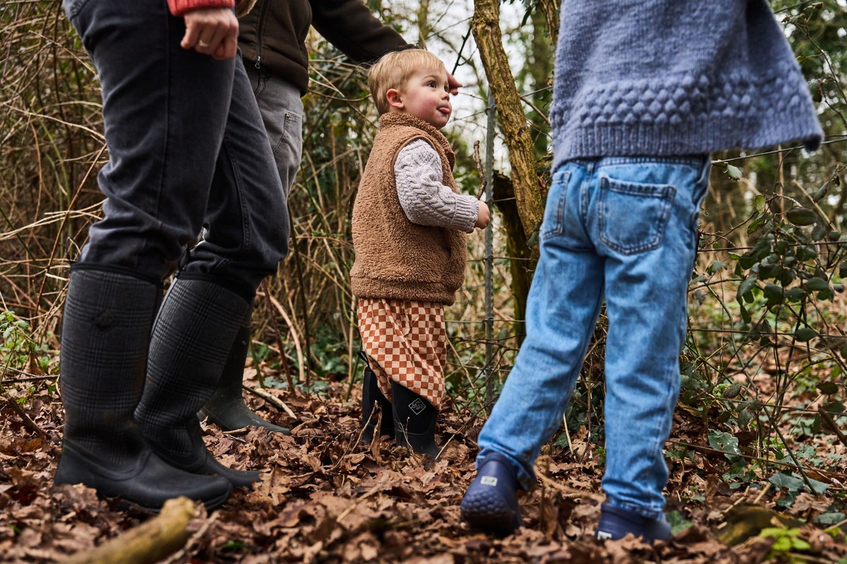Familie mit Kleinkind im Wald, alle tragen Muck Boots, Kind im Mini-Muck.