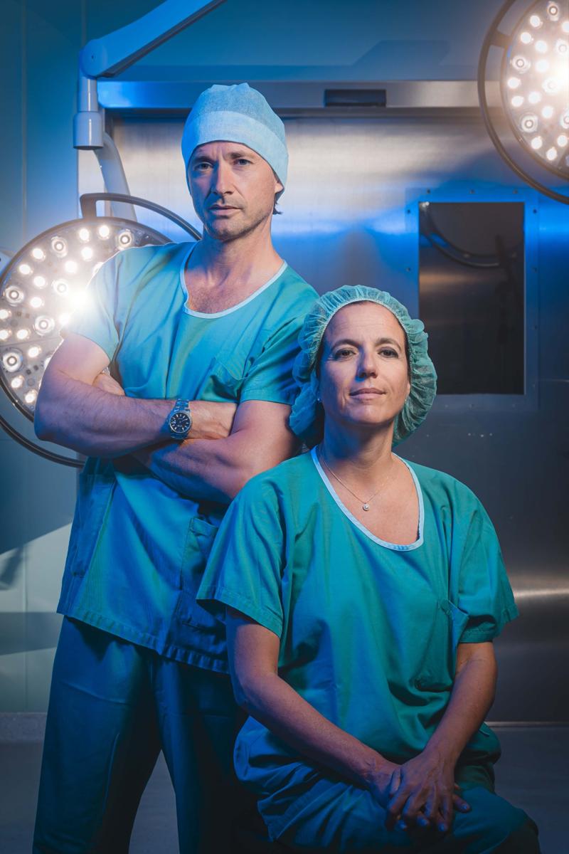 substantial-times-die-bruecke-ueber-das-unmoegliche-gregoire-courtine-rolex-award-11 Grégoire Courtine und die Neurochirurgin Jocelyne Bloch in OP-Kleidung, vor einer leuchtenden Operationslampe stehend beziehungsweise sitzend; beide blicken ernst und konzentriert in die Kamera.