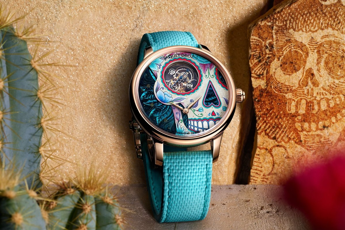 Armbanduhr Jaquet Droz Tourbillon Red Gold – Catrina Skull auf sandfarbenem Hintergrund mit Kaktus und Steinrelief eines Totenkopfes. Die Uhr besitzt ein roségoldenes Gehäuse, ein türkisfarbenes Armband und ein farbenreich bemaltes Zifferblatt mit dem Motiv einer stilisierten Catrina in Blau-, Rosa- und Türkistönen.