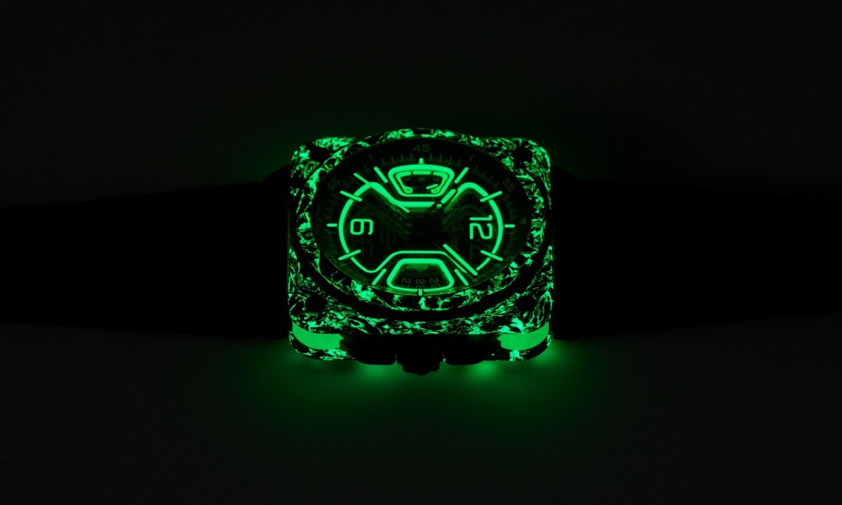 substantial-times-mehr-zeit-als-wir-08 Eine quadratische Armbanduhr von Bell & Ross, deren Gehäuse, Zifferblatt und Indizes im Dunkeln intensiv grün leuchten. Das Gehäuse zeigt eine marmorierte Struktur mit schwarzen und leuchtgrünen Elementen, während die Zeiger und Ziffern ebenfalls grün schimmern. Die Uhr liegt auf schwarzem Hintergrund und scheint selbst zu leuchten.