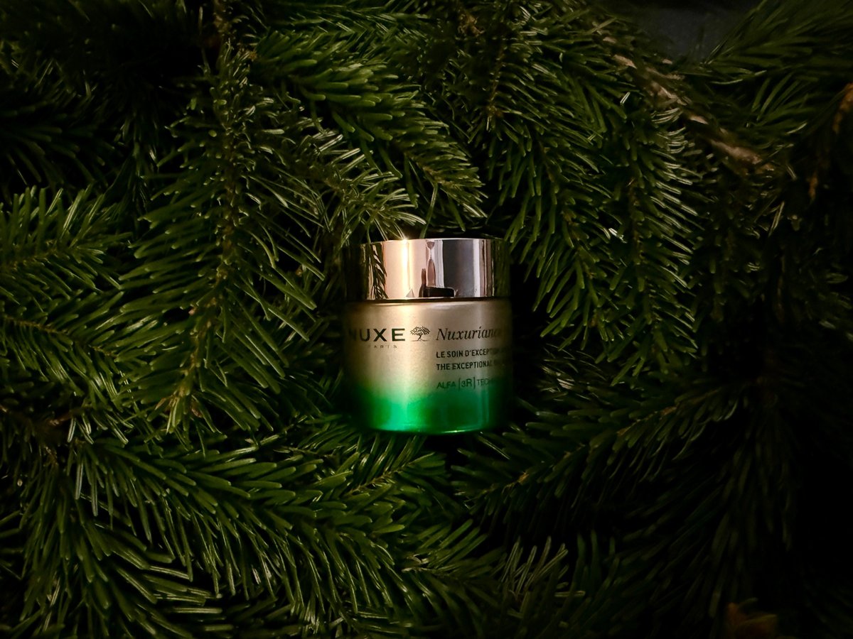 Ein Tiegel der Nuxe-Nuxuriance-Ultra-Creme steht zwischen dichten Tannenzweigen.