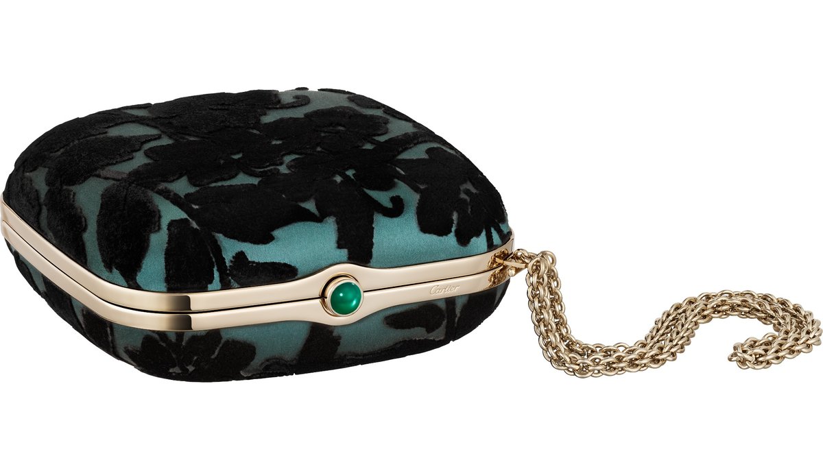 Eine quadratische Abendtasche von Cartier aus smaragdgrünem Satinstoff mit schwarzem floralen Tufting-Muster und goldfarbener Fassung mit grünem Onyx-Cabochon. Daneben liegt eine goldfarbene Kettentrageschlaufe.