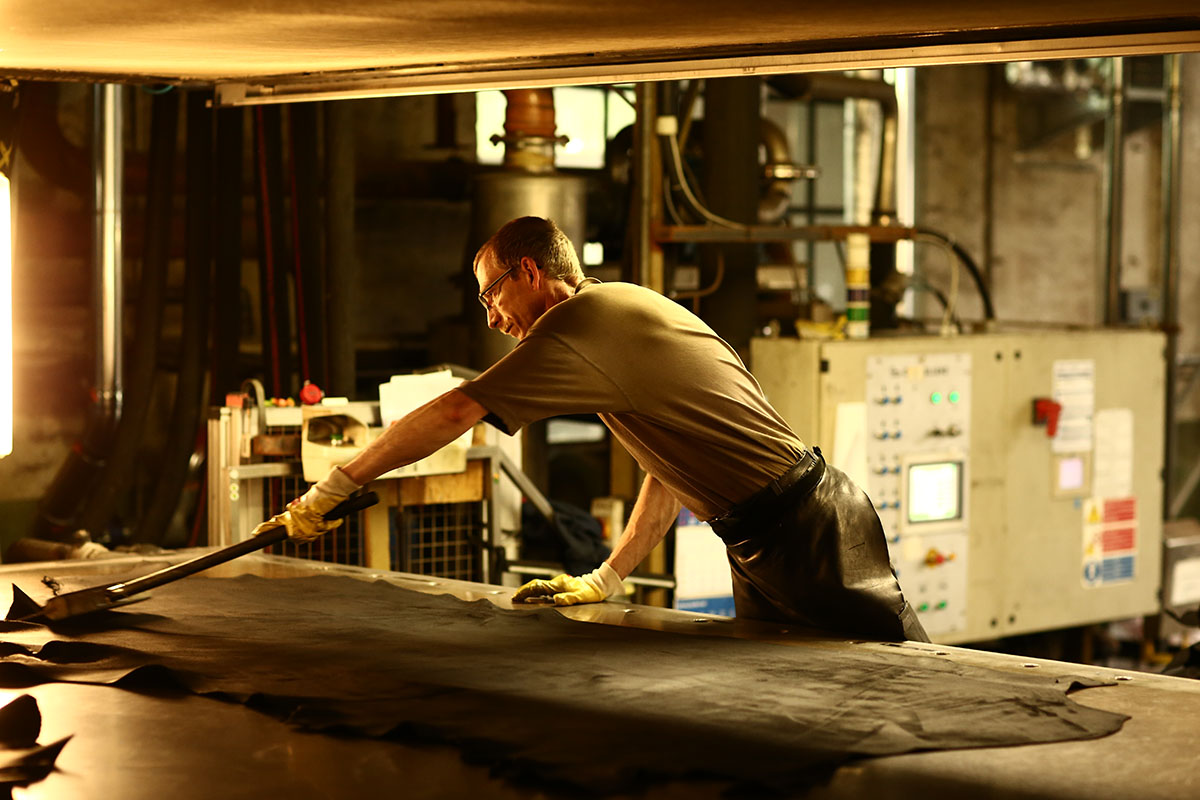 substantial-times-wir-haben-verlernt-materialien-mit-wuerde-zu-behandeln-05 Ein Mitarbeiter streicht eine frisch bearbeitete Lederhaut auf dem Vakuumtrockner glatt, um eine gleichmäßige Oberfläche zu erzielen.