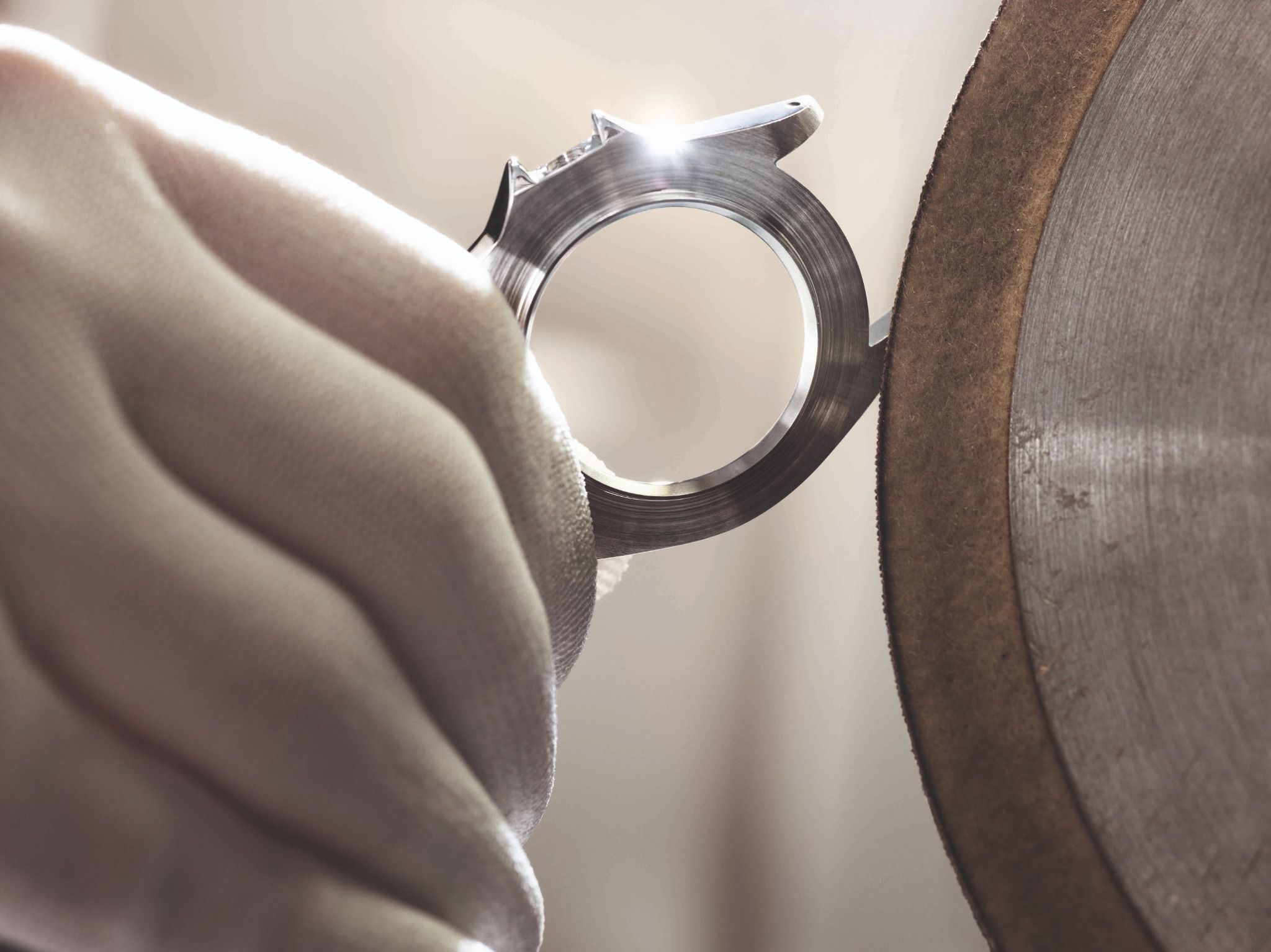 Detailansicht des Mittelgehäuses einer Rolex Armbanduhr während der Aufarbeitung an einer Polierscheibe.