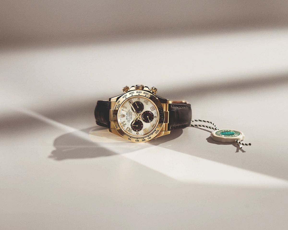 Eine Rolex Oyster Perpetual Cosmograph Daytona in Gelbgold mit Lederarmband und Certified-Pre-Owned-Siegel auf hellem Untergrund.