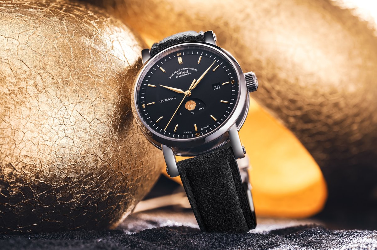 Elegante Armbanduhr mit anthrazitfarbenem Zifferblatt und Mondphasenanzeige von Mühle-Glashütte vor warmem Hintergrund