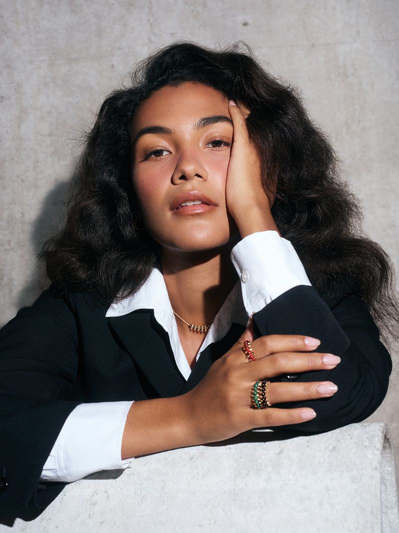 Porträt von Sängerin Olivia Dean. Sie trägt eine Halskette aus Roségold mit schwarzem Onyx-Anhänger sowie mehrere Ringe aus Roségold mit Onyx und farbigem Achat.