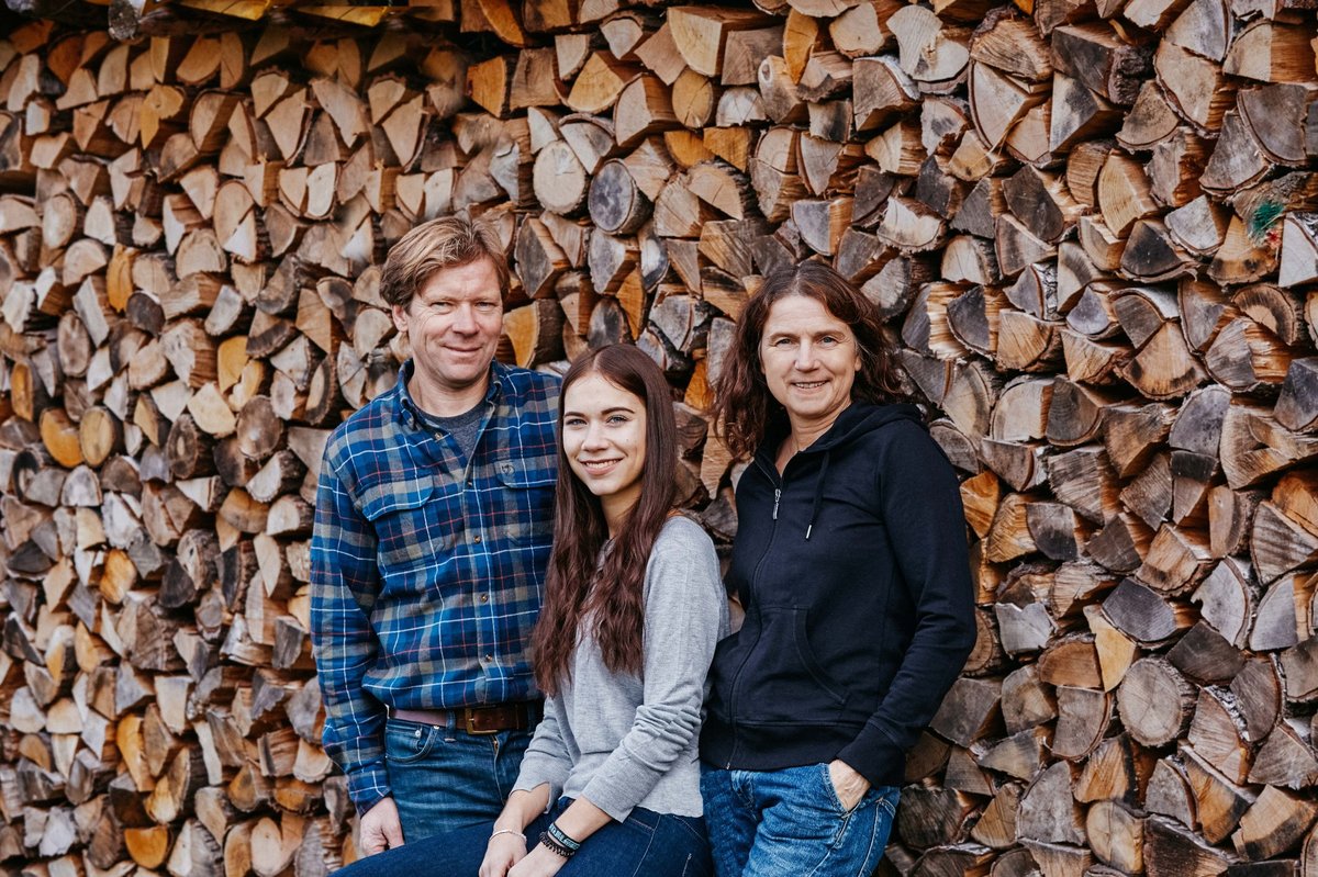 Michael Andres mit seiner Frau Ursula und Tochter Elena vor einem Holzstapel