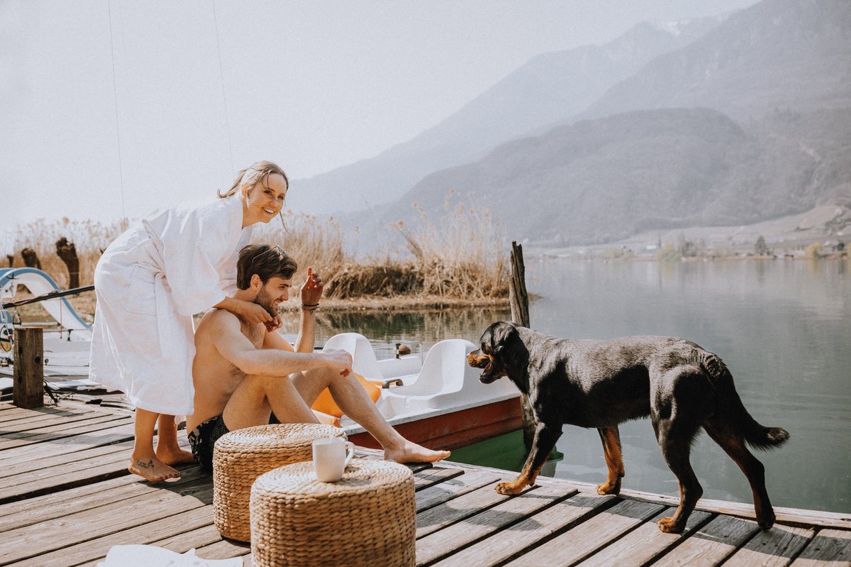 Paar mit Hund auf einem Steg am Kalterer See
