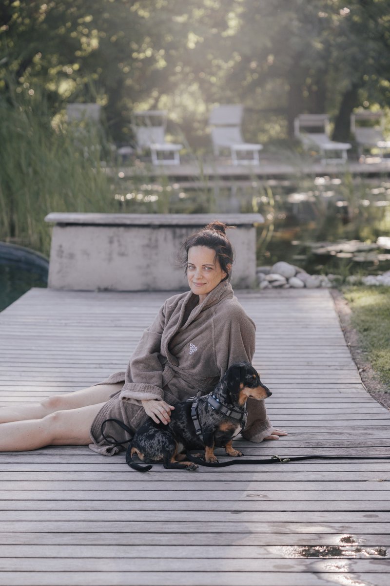 Frau im Bademantel mit Dackel am Naturpool