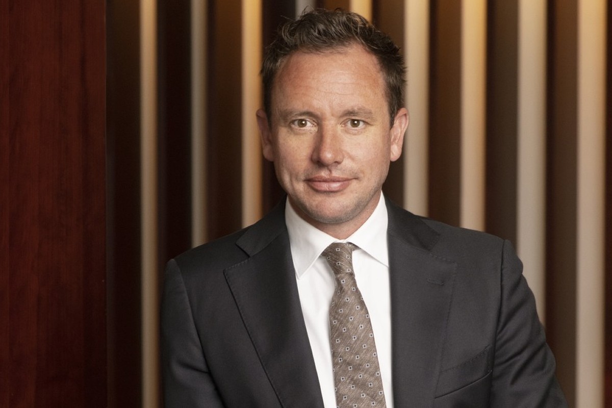 Porträt von Niels Eggerding im Anzug mit Krawatte vor warm beleuchtetem Innenraum