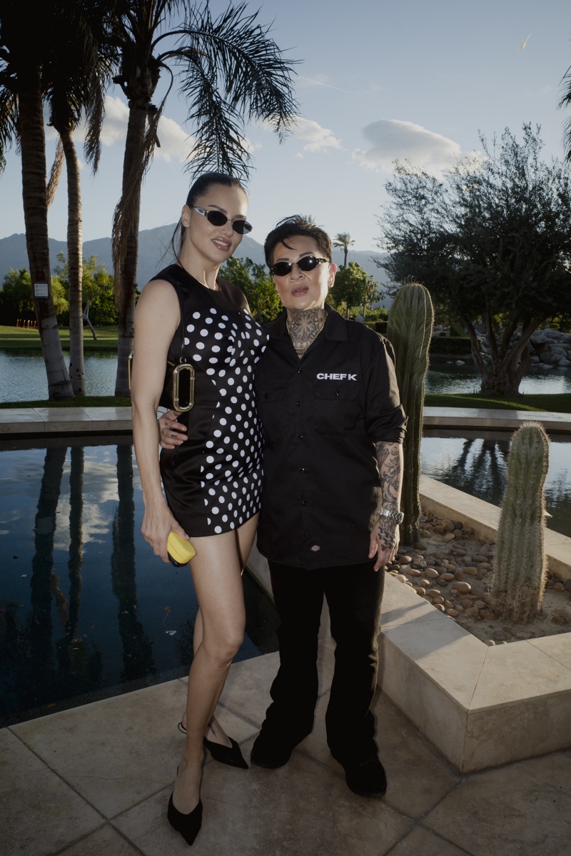 Adriana Lima und Chefköchin Chef K stehen am Pool einer Villa in Palm Springs und tragen schmale schwarze Sonnenbrillen