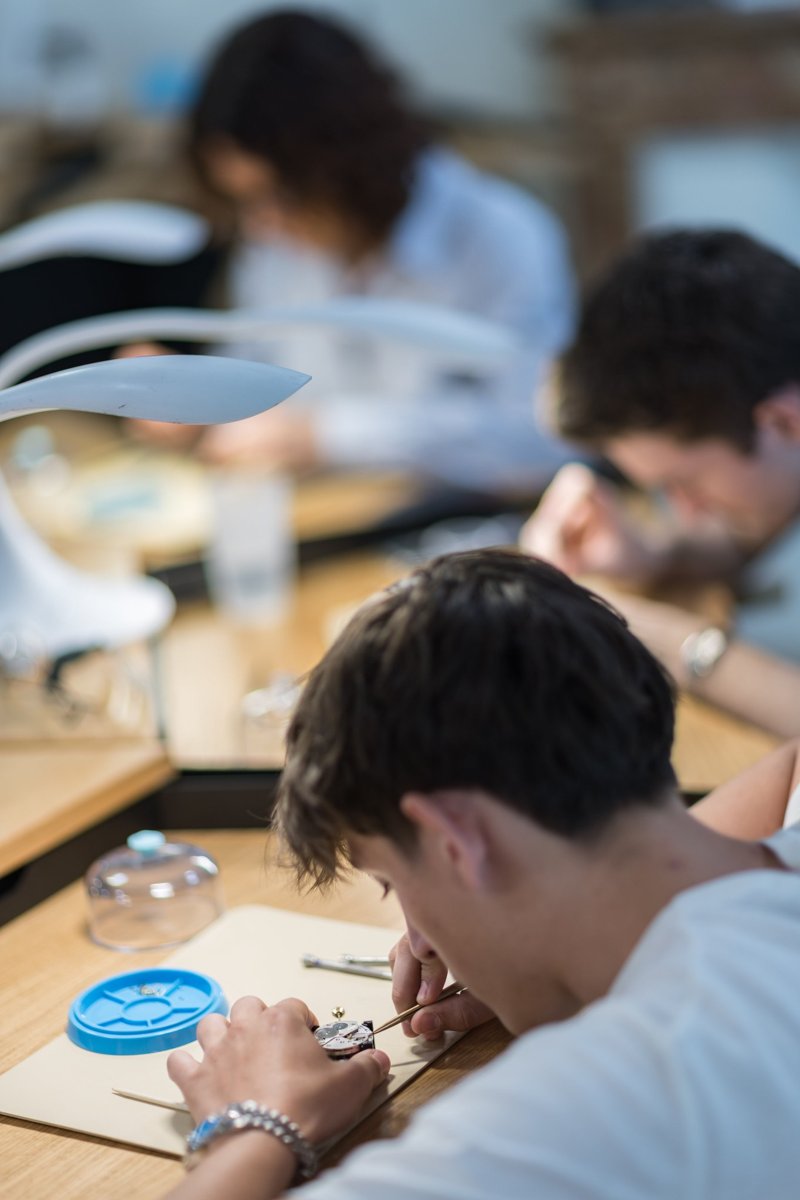 Teilnehmer setzen bei einem Initium-Workshop in Genf mit Werkzeugen ein mechanisches Uhrwerk zusammen
