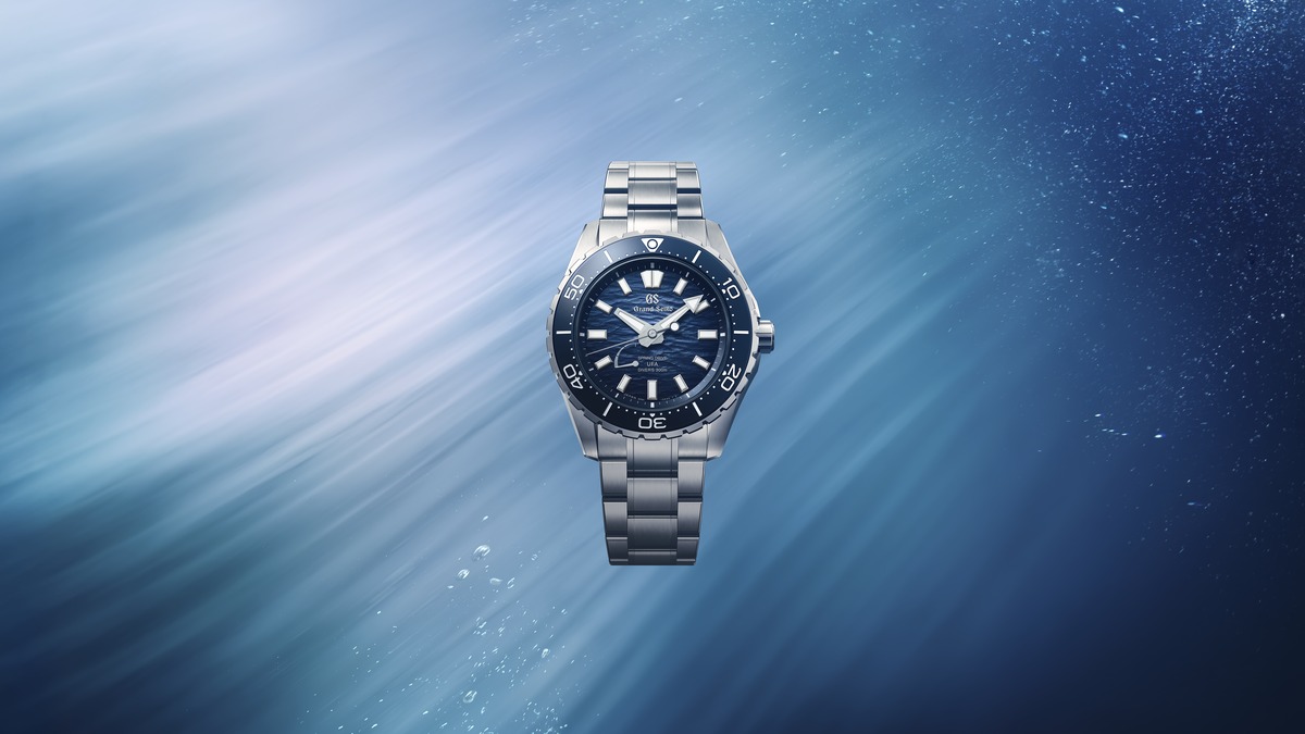 Inszenierte Aufnahme der Uhr Ushio bei Tageslicht vor einem meerartig schillernden blauen Hintergrund