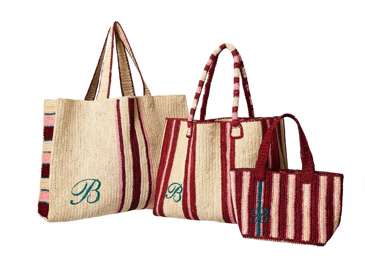 Drei gestreifte Raffia-Taschen in Natur- und Rottönen mit gesticktem grünen „B“ stehen vor hellem Hintergrund, in unterschiedlichen Größen angeordnet.