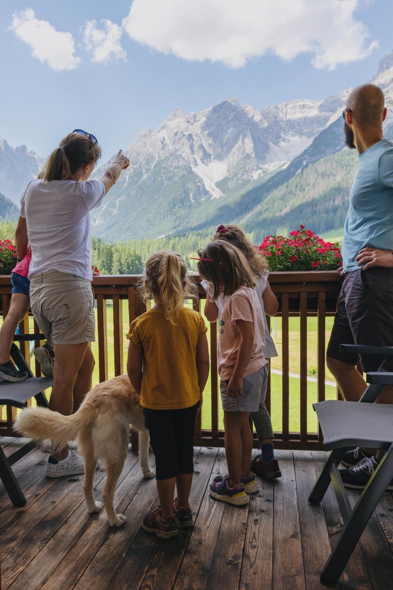 substantial-times-family-resort-rainer-02 Familie mit Hund auf einem Balkon des Family Resort Rainer mit Blick auf die Dolomiten in Südtirol