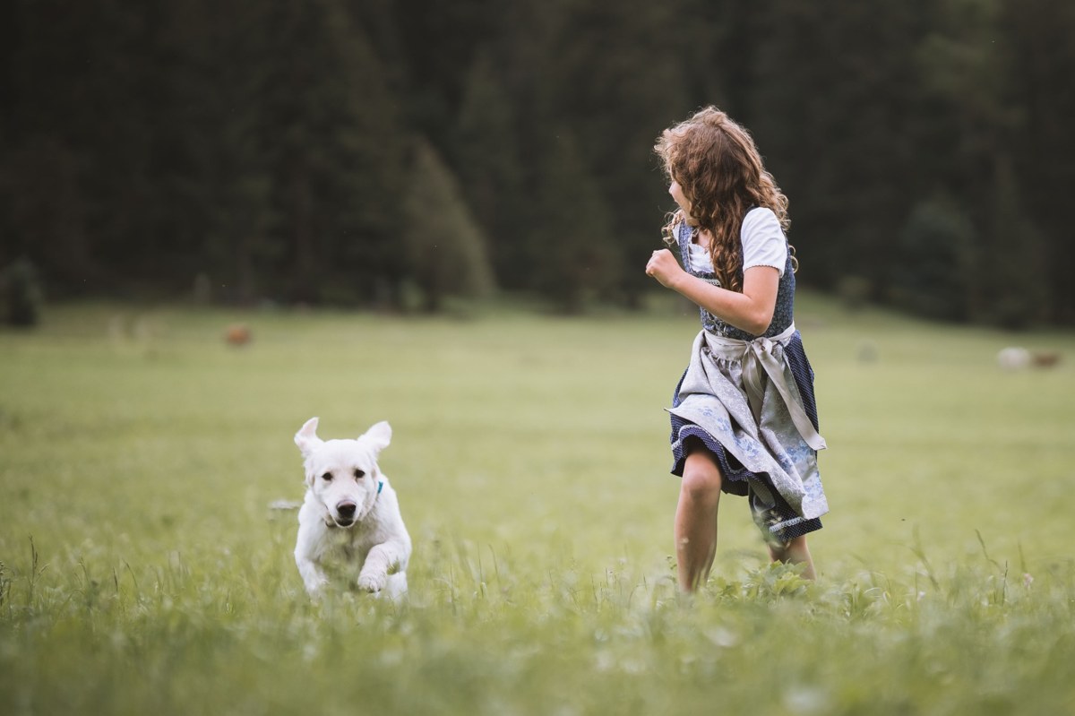 substantial-times-garberhof-07 Mädchen und Hund laufen gemeinsam über eine Wiese im Antholzertal