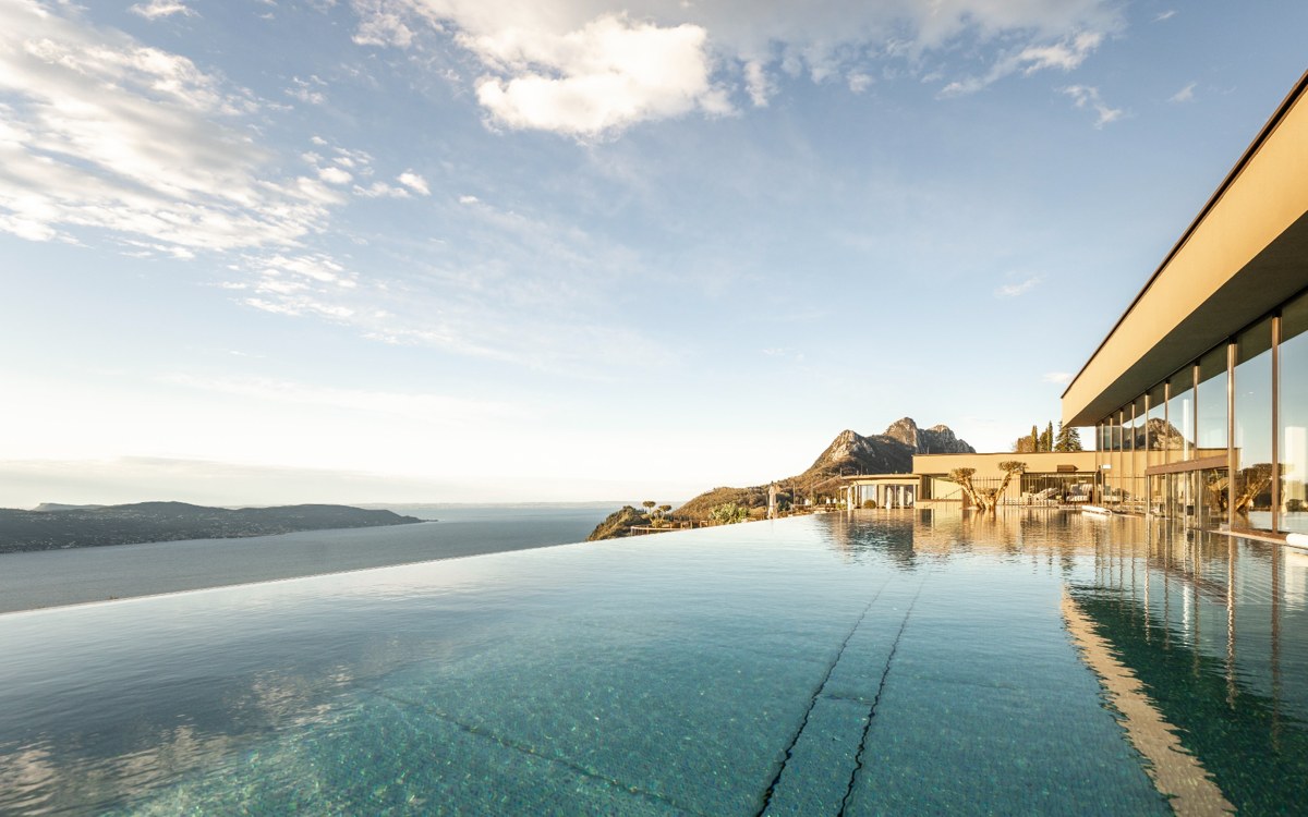 substantial-times-stroblhof-lake-garda-01 Infinity-Pool des Stroblhof Lake Garda mit Blick auf den Gardasee und die umliegenden Berge. Das Resort in Gargnano verbindet Wellnessurlaub und Urlaub mit Hund am Gardasee