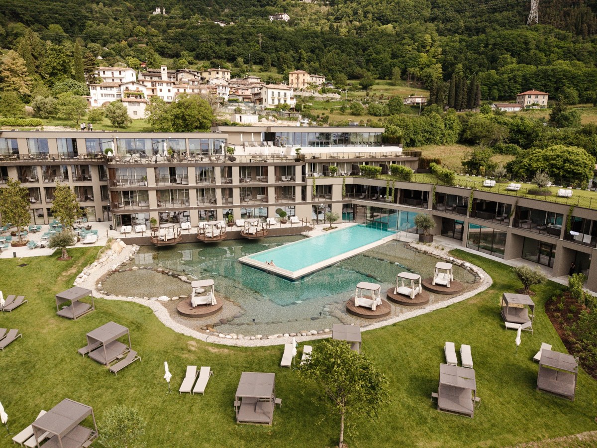 substantial-times-stroblhof-lake-garda-02 Außenansicht des Stroblhof Lake Garda mit Naturbadeteich, Poollandschaft und Gartenanlage in Gargnano am Gardasee