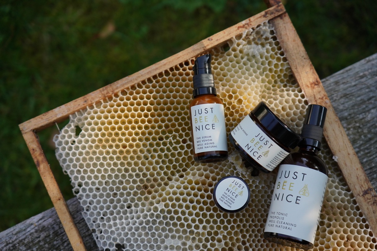 Vier Pflegeprodukte von Just Bee Nice auf einer Bienenwabe