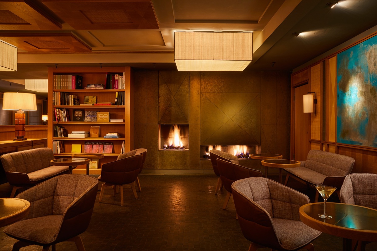 Lobby des Louis Hotel München mit Sesseln, Kaminen und warmem Licht