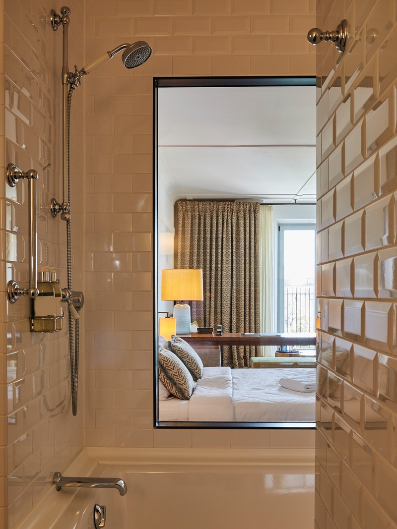 09_Louis_Hotel_Muenchen Bad mit weißen Metro-Kacheln und Blick ins Zimmer des Louis Hotels München