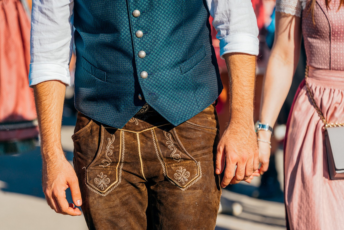 Mann in Lederhose und Trachtenweste neben einer Frau im Dirndl mit Uhr am Handgelenk