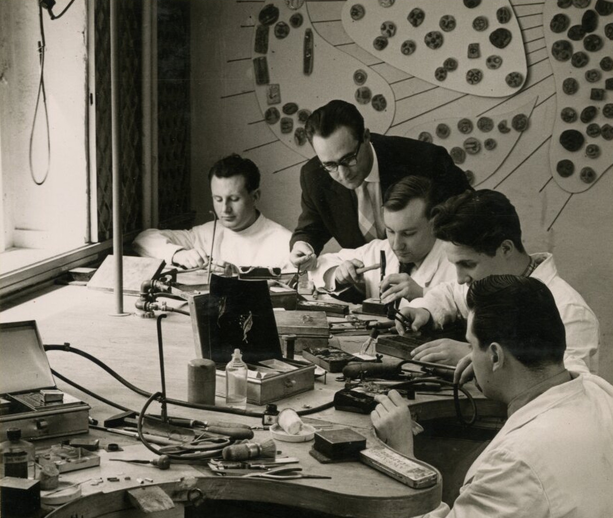 substantial-times-1957-1958-rk-in-der-goldschmiedewerkstatt René Kern mit vier Goldschmieden bei der Arbeit in seiner Werkstatt an der Düsseldorfer Königsallee in den 1950er-Jahren
Bildunterschrift
Credit
Foto: Archiv Familie Kern (Fotograf unbekannt)