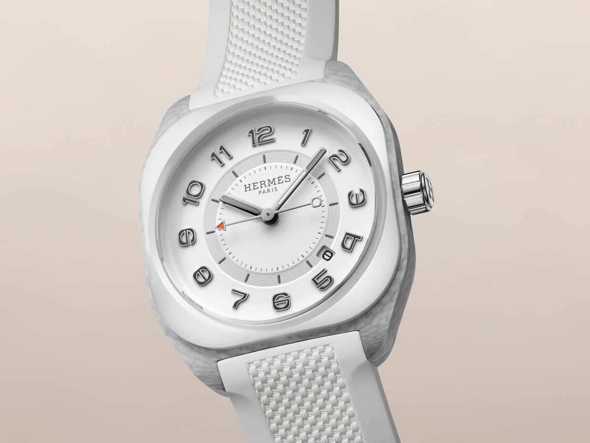 Hermès H08 mit weißer Keramiklünette, hellem Zifferblatt, grau strukturiertem Gehäuse und weißem Kautschukarmband in schräger Ansicht